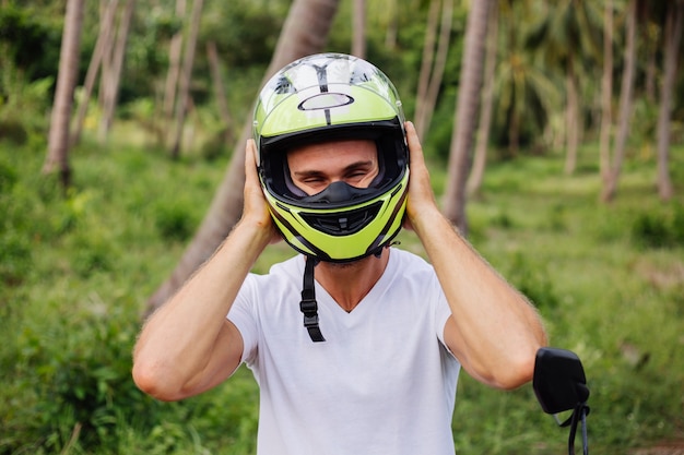 Homme fort sur le champ de la jungle tropicale avec moto rouge