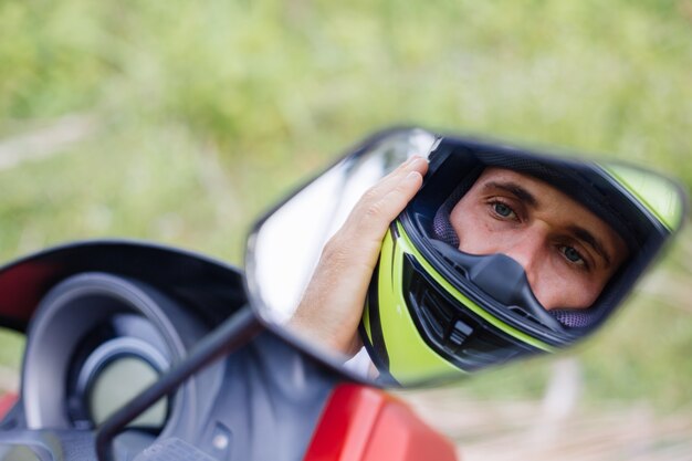 Homme fort sur le champ de la jungle tropicale avec moto rouge