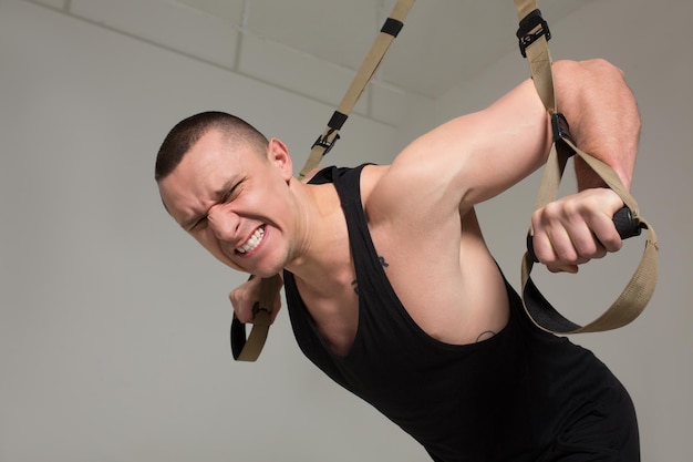 Homme fort en uniforme sportif noir s'entraînant dur au gymnase. Notion de sport.