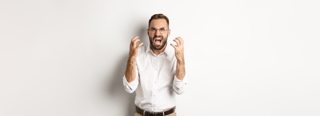 Homme frustré et en colère criant de rage se serrant la main furieux debout sur fond blanc