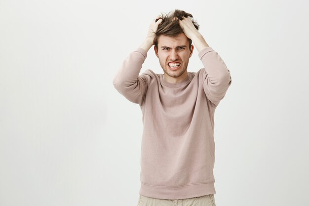 Homme frustré en détresse jetant les cheveux et grimaçant anxieux