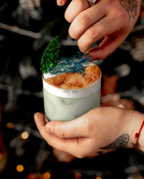 Homme garni d'un verre de cocktail avec des décorations vertes