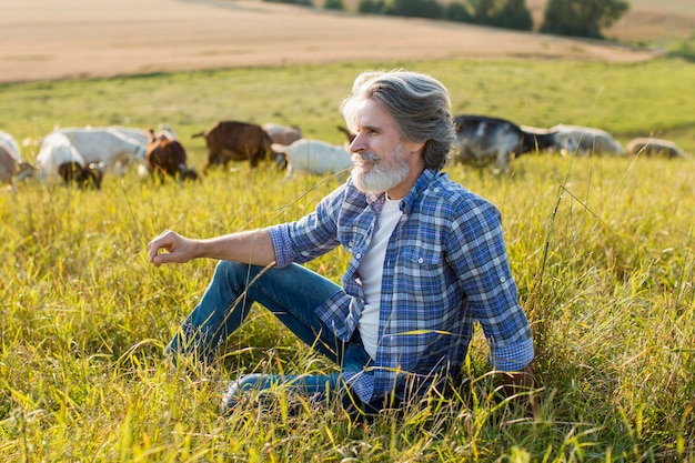 Homme grand angle avec des chèvres à la ferme