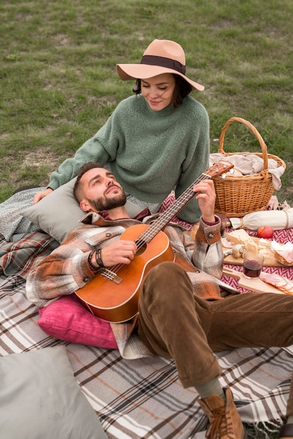 Homme grand angle portant sur les genoux de la petite amie et jouant de la guitare