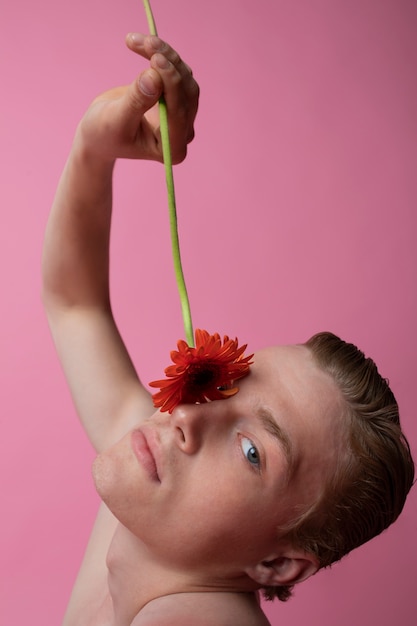 Homme grand angle posant avec une fleur rouge