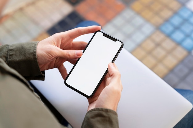 Homme grand angle regardant son téléphone avec écran vide