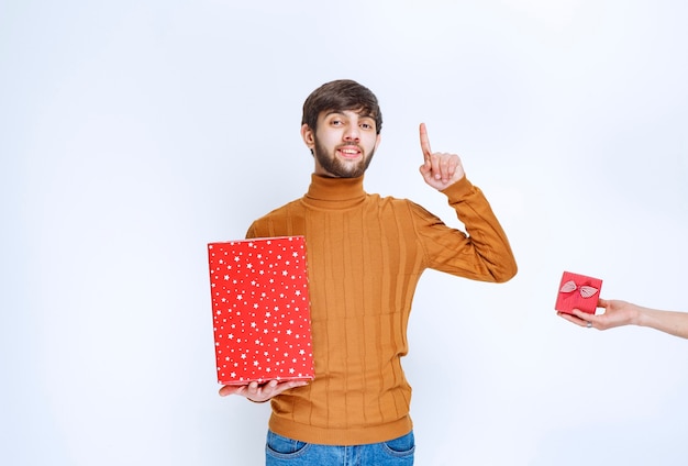 L'homme a une grande boîte-cadeau rouge et se voit également offrir une petite.