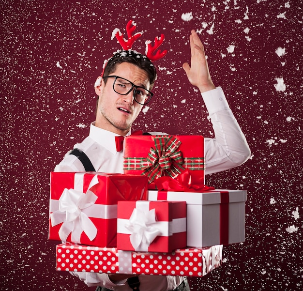 Photo gratuite homme grimaçant avec pile de cadeaux de noël