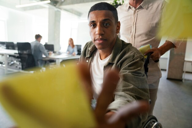 Photo gratuite homme handicapé en fauteuil roulant travaillant à son travail de bureau