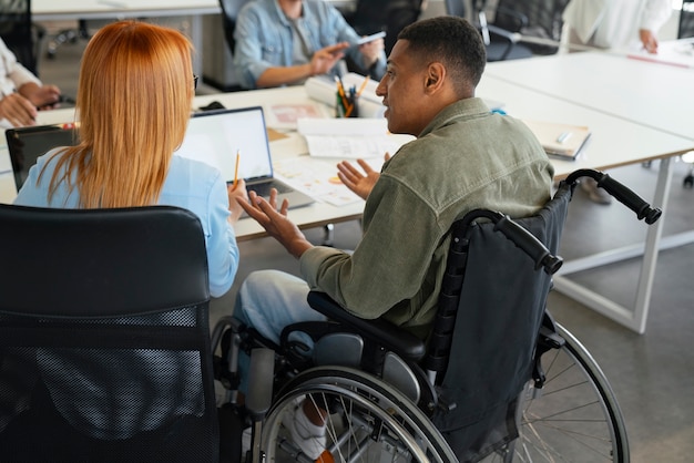 Photo gratuite homme handicapé en fauteuil roulant travaillant à son travail de bureau