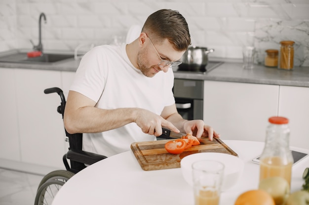 Homme handicapé, préparer la nourriture dans la cuisine. Couper les légumes.