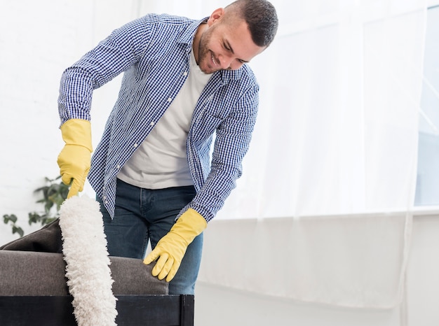 Photo gratuite homme heureux à l'aide d'un plumeau