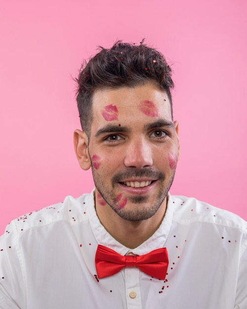 Photo gratuite homme heureux avec des marques de rouge à lèvres kiss sur le visage