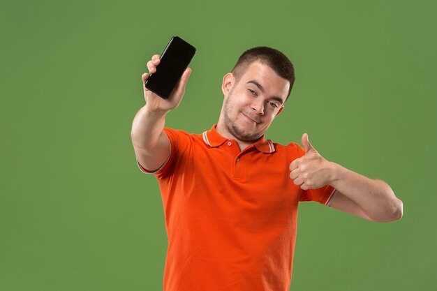 L'homme heureux montrant à l'écran vide du téléphone mobile contre le vert.