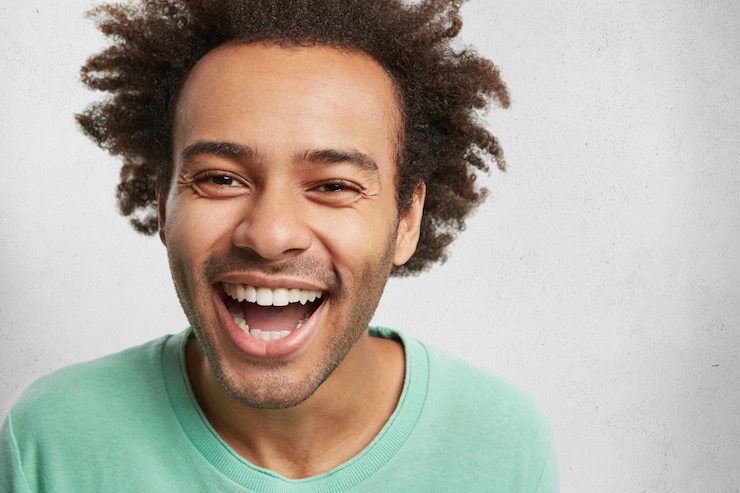 Photo gratuit homme heureux ravi avec une peau foncée et une coiffure touffue, sourit à la caméra, exprime des émotions positives