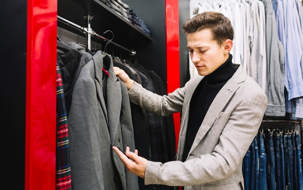 Homme heureux vérifiant l&#39;étiquette de prix du manteau en magasin