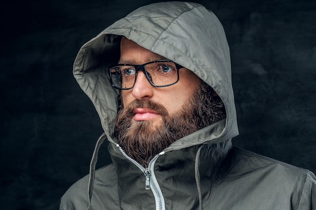 Homme hipster barbu brutal dans une hotte sur fond gris.