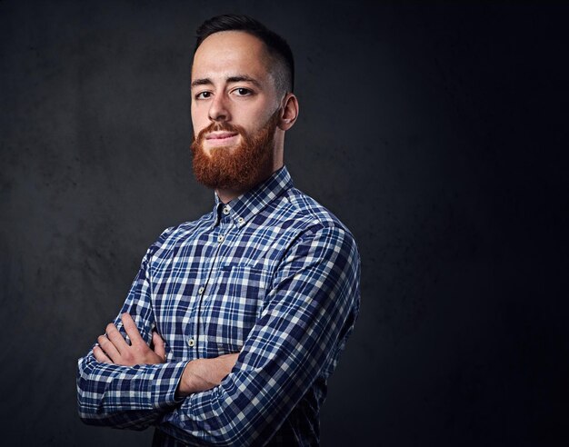 Homme hipster barbu rousse réfléchie avec les bras croisés, vêtu d'une chemise polaire bleue.