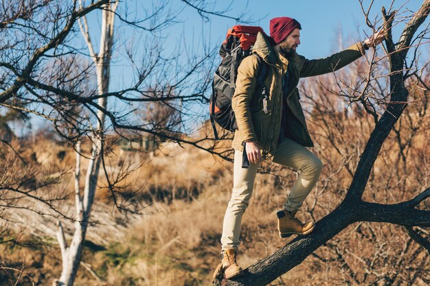 Homme hipster voyageant avec sac à dos dans la forêt d'automne portant veste chaude, chapeau, touriste actif, découverte de la nature en saison froide