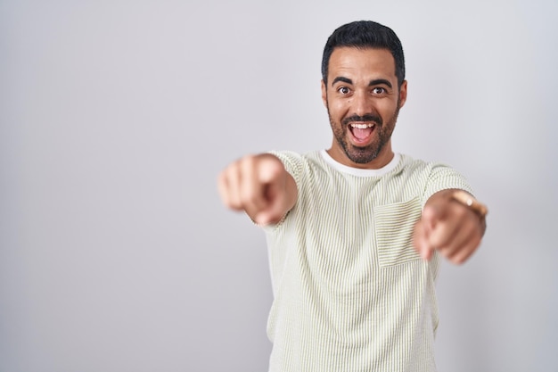 Photo gratuite homme hispanique avec barbe debout sur fond isolé pointant vers vous et la caméra avec les doigts souriant positif et joyeux