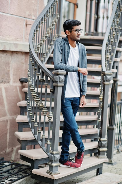 Photo gratuite un homme indien élégant à lunettes porte des vêtements décontractés posés en plein air contre des escaliers en fer