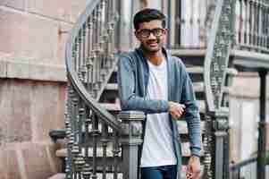 Photo gratuite un homme indien élégant à lunettes porte des vêtements décontractés posés en plein air contre des escaliers en fer