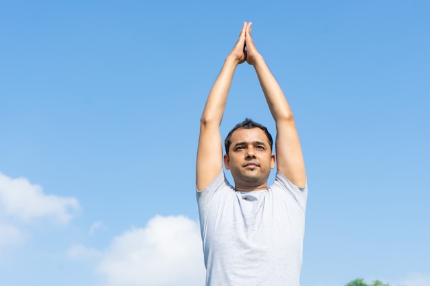 Homme indien, faire du yoga et presser les mains ensemble au-dessus de la tête à l&#39;extérieur
