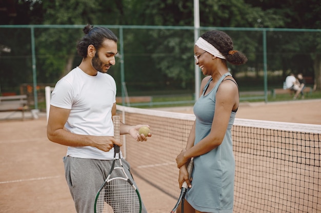 Homme indien et femme noire américaine debout sur un court de tennis