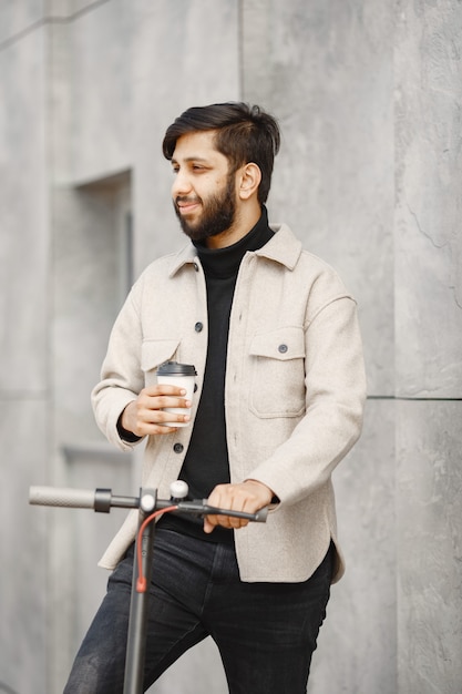 Homme indien monté sur un scooter électrique. Homme avec du café.