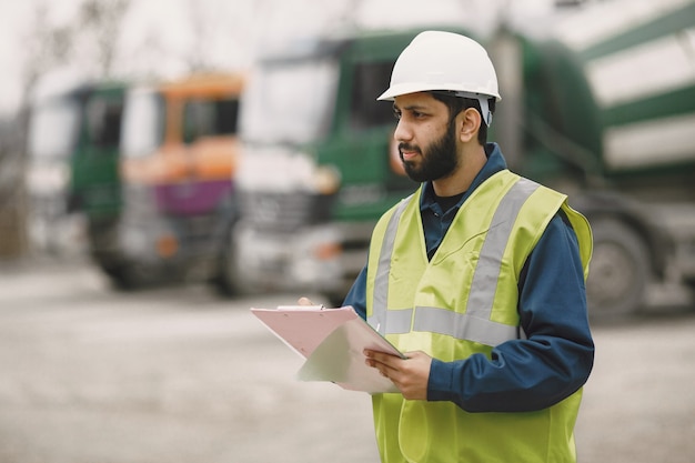 Homme indien travaillant. Mâle dans un gilet jaune. Homme avec dossier.