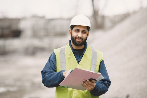 Homme indien travaillant. Mâle dans un gilet jaune. Homme avec téléphone portable.