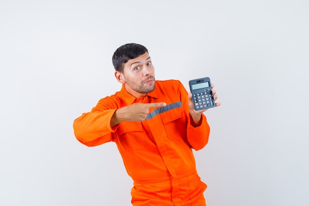 Homme industriel pointant sur la calculatrice en uniforme et à la recherche optimiste. vue de face.