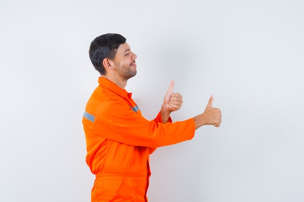 Homme industriel en uniforme montrant deux pouces vers le haut et à la joyeuse.