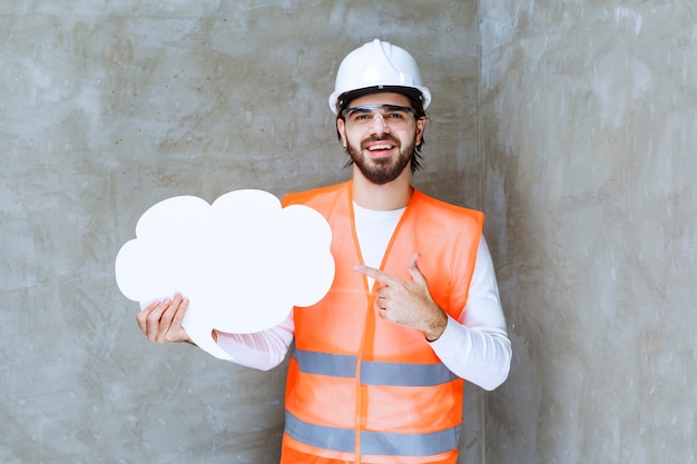 Homme ingénieur en casque blanc et lunettes de protection tenant un tableau d'information en forme de .