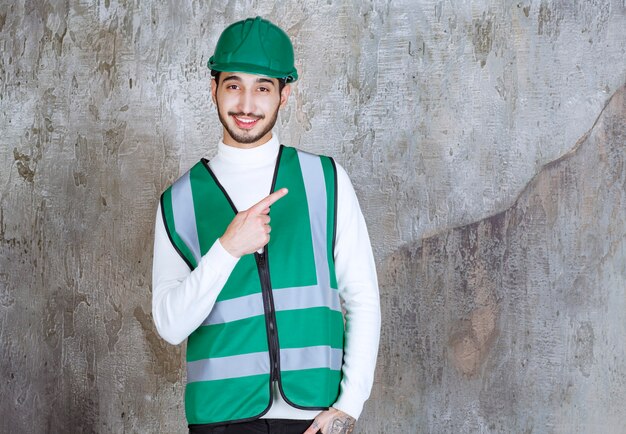 Homme ingénieur en uniforme jaune et casque montrant le côté droit.