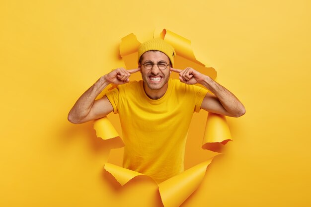 Un homme irrité se bouche les oreilles à deux mains, ignore le mauvais son