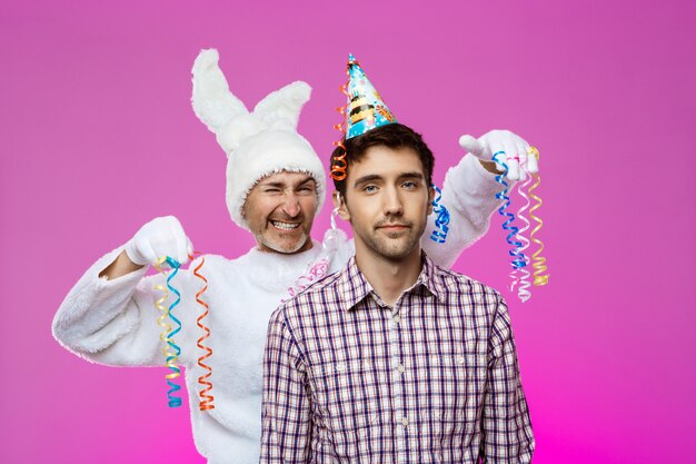 Homme ivre et lapin à la fête d'anniversaire sur le mur violet.