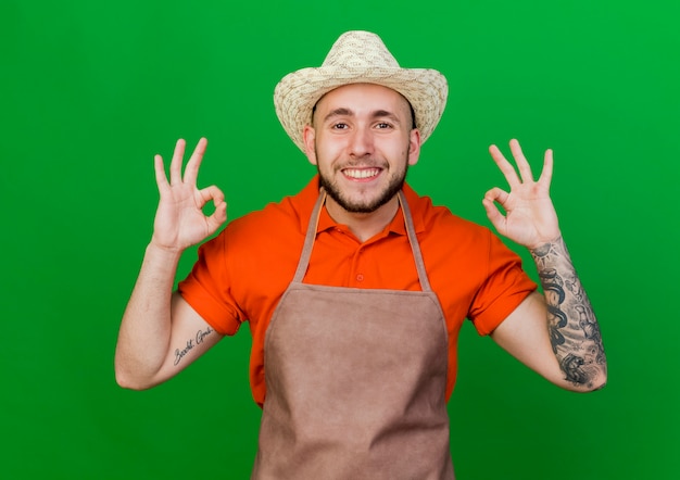 Photo gratuite homme jardinier souriant portant des gestes de chapeau de jardinage signe de la main ok avec les deux mains