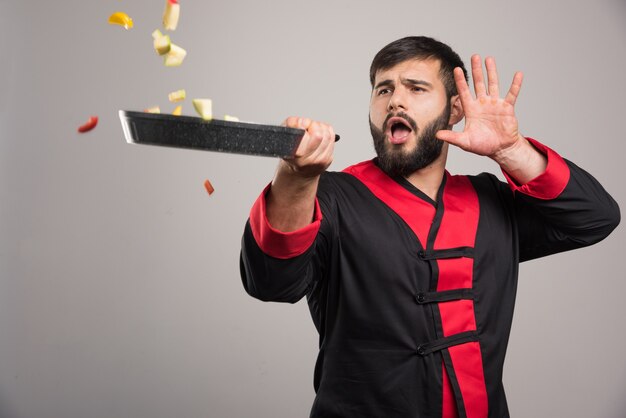 Homme jetant des légumes de la casserole.