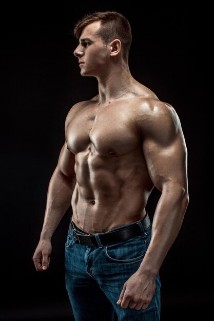 Homme jeune bodybuilder sur fond noir. Torse masculin. soulagement musculaire