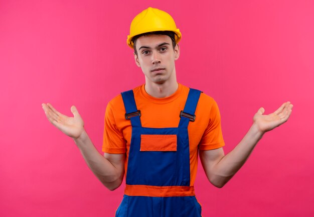 Homme jeune constructeur portant un uniforme de construction et un casque de sécurité est confus