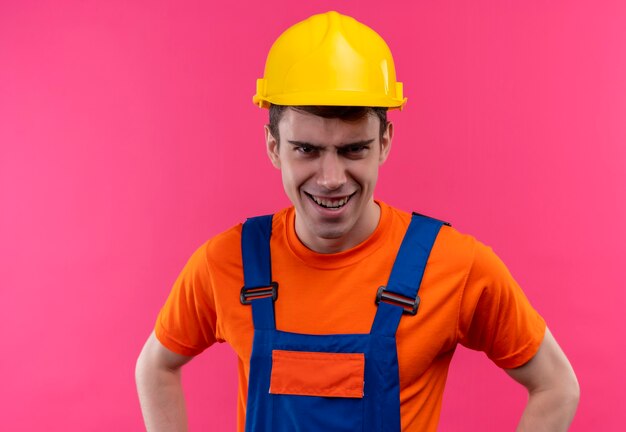 Homme jeune constructeur portant des uniformes de construction et un casque de sécurité en riant