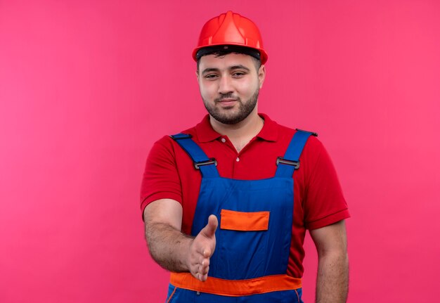 Homme jeune constructeur en uniforme de construction et casque de sécurité avec quelqu'un offrant la main