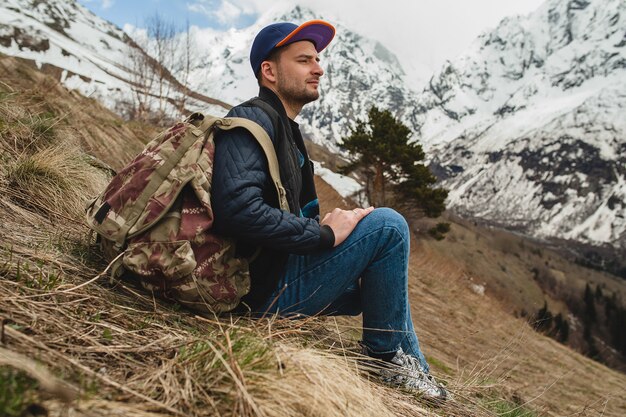 Homme jeune hipster assis dans les montagnes