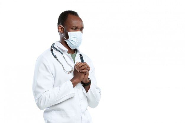 Homme jeune médecin avec stéthoscope et masque facial isolé sur blanc