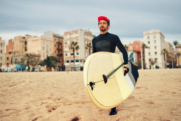 Homme jeune surfeur sur la plage avec planche de surf