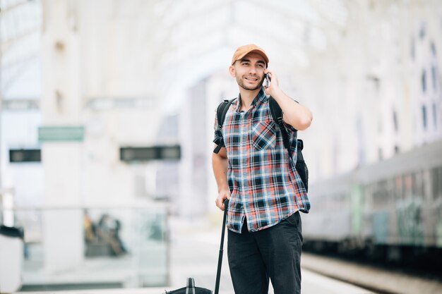 Photo gratuite homme jeune voyageur parlant au téléphone à la gare