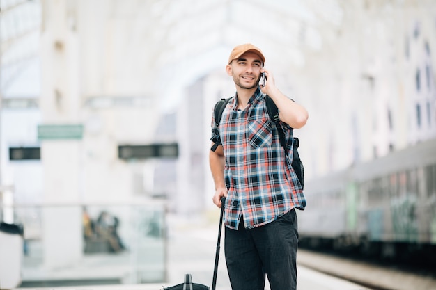 Homme jeune voyageur parlant au téléphone à la gare