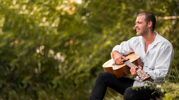 Homme jouant de la guitare dans l'espace copie nature