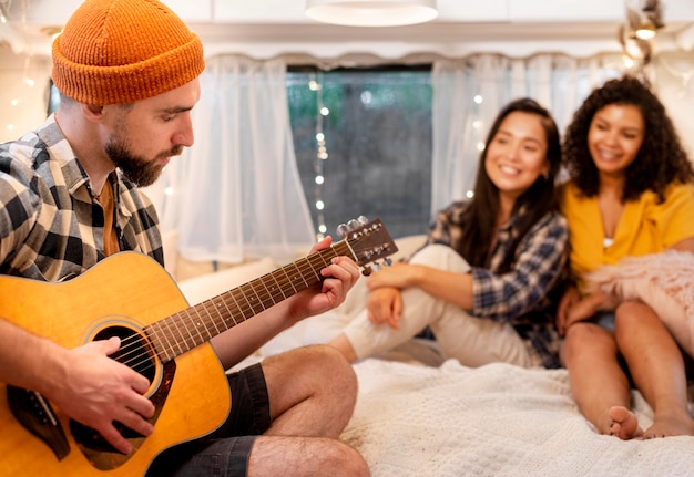 Photo gratuite homme jouant de la guitare et femmes écoutant